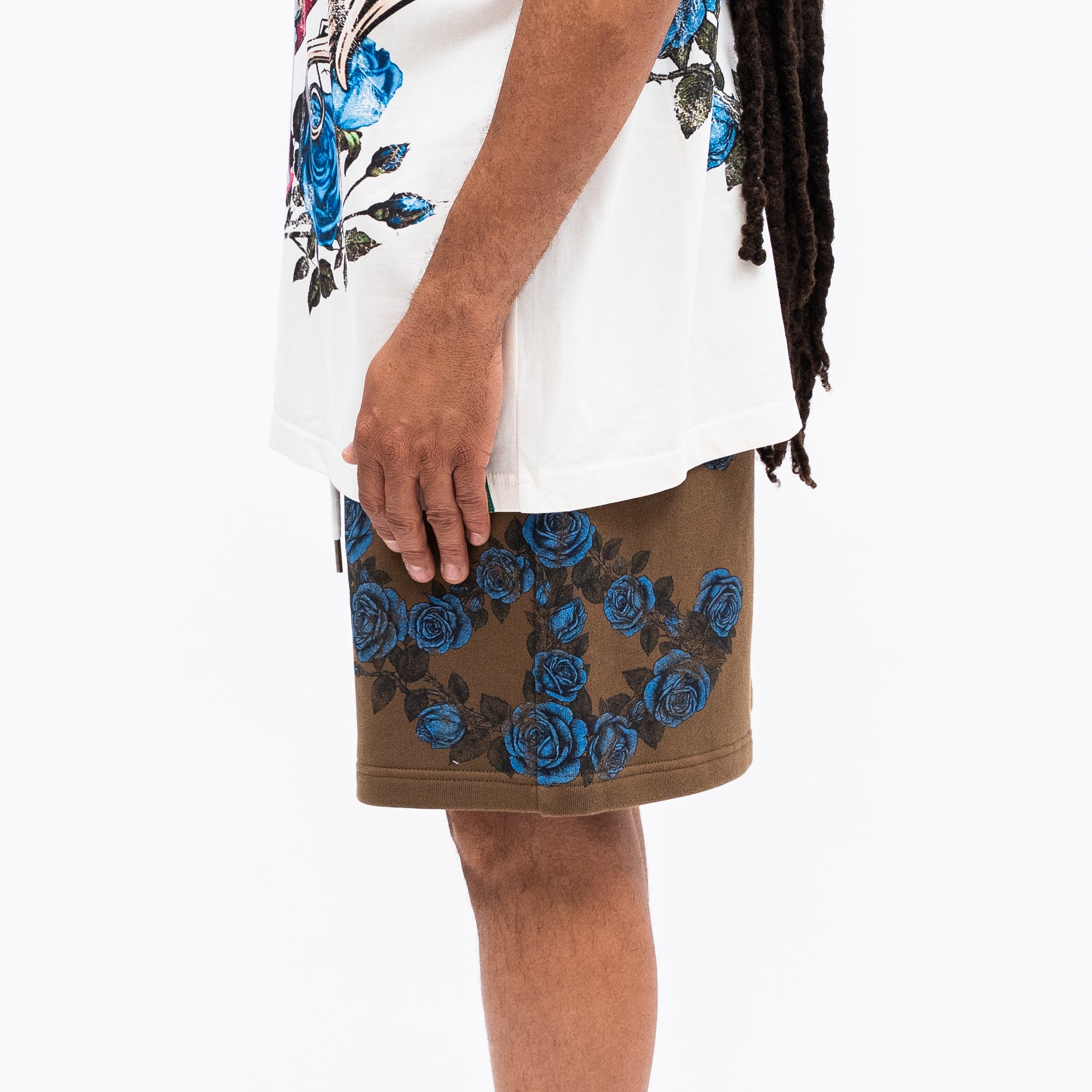 Person wearing a white top with floral designs and a brown skirt with blue rose patterns on a white background