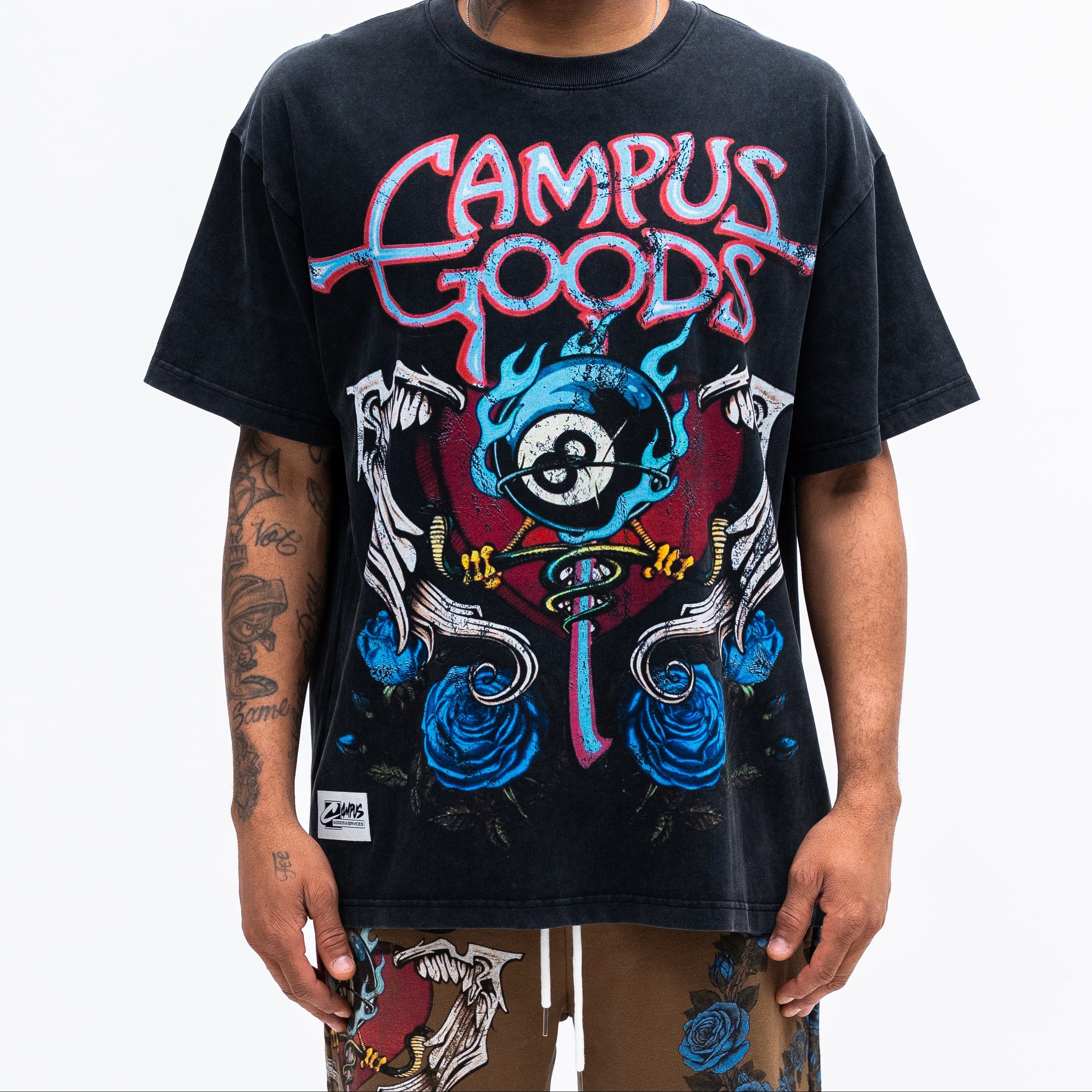 Person wearing a black 'Campus Goods' t-shirt with colorful graphics on a white background