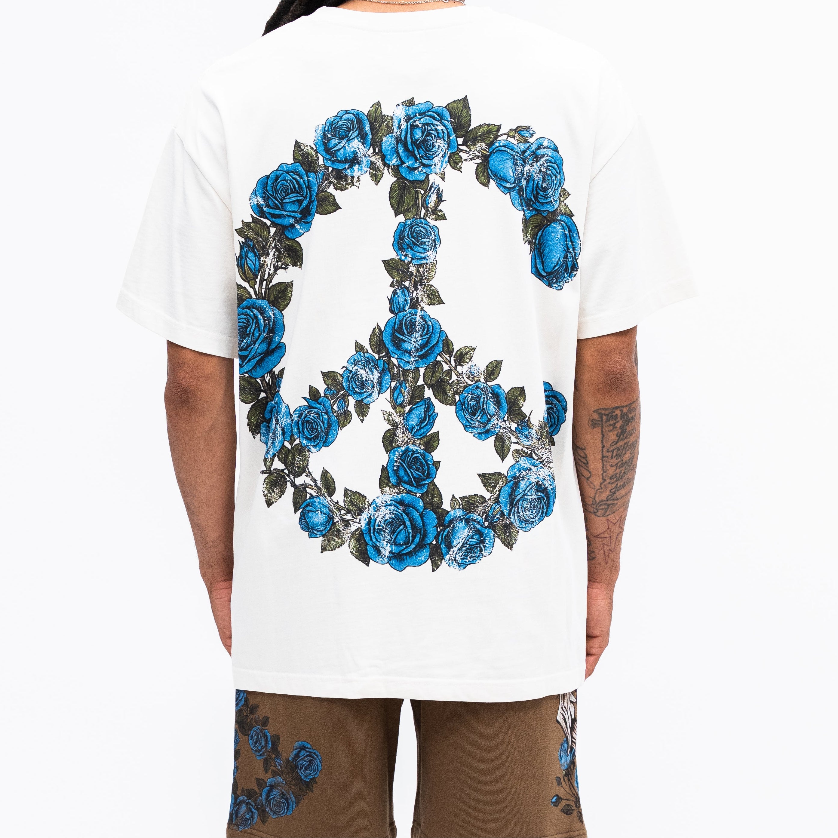 Person wearing a white t-shirt with a blue floral peace symbol design on the back.