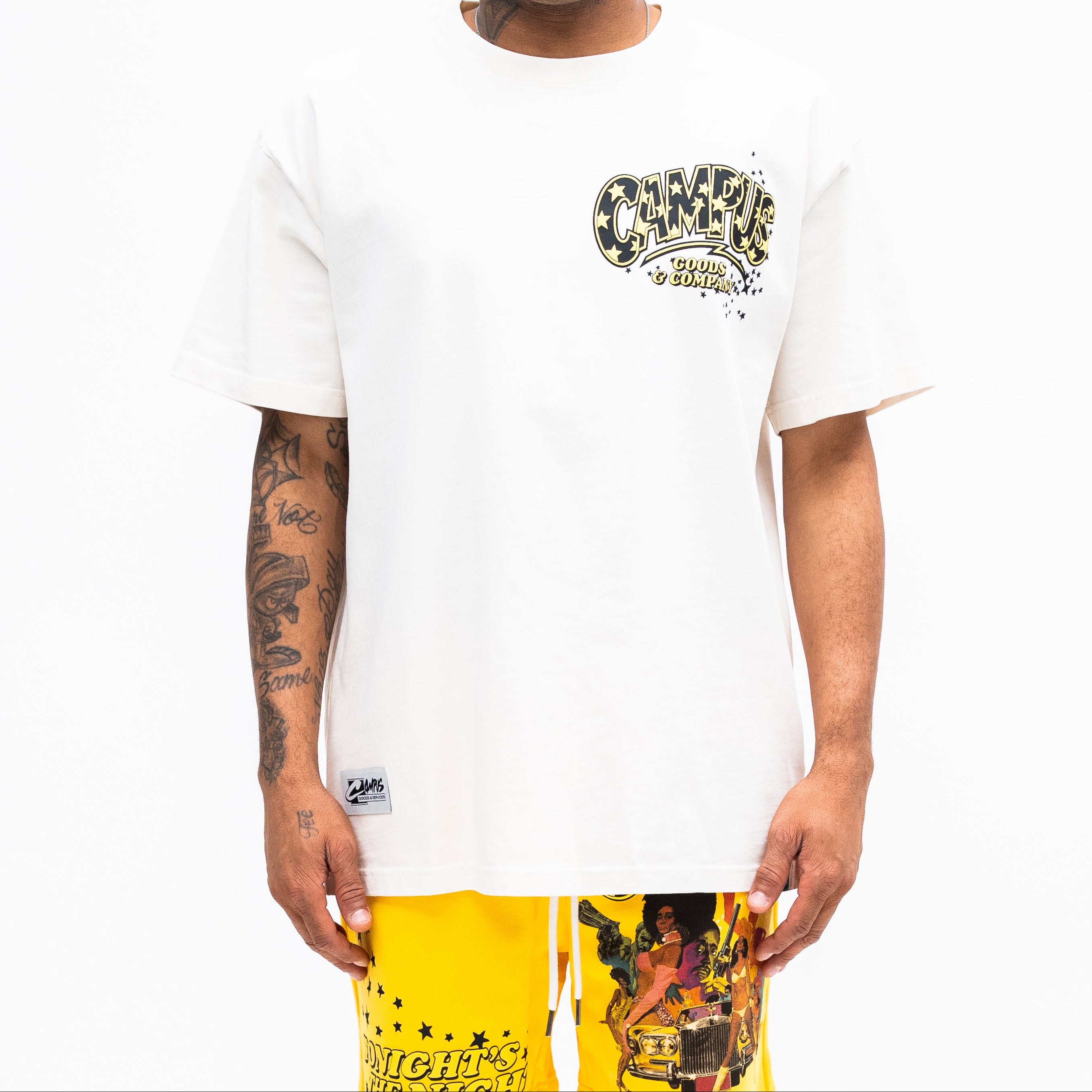 Man wearing a white t-shirt with a graphic design and yellow pants on a white background