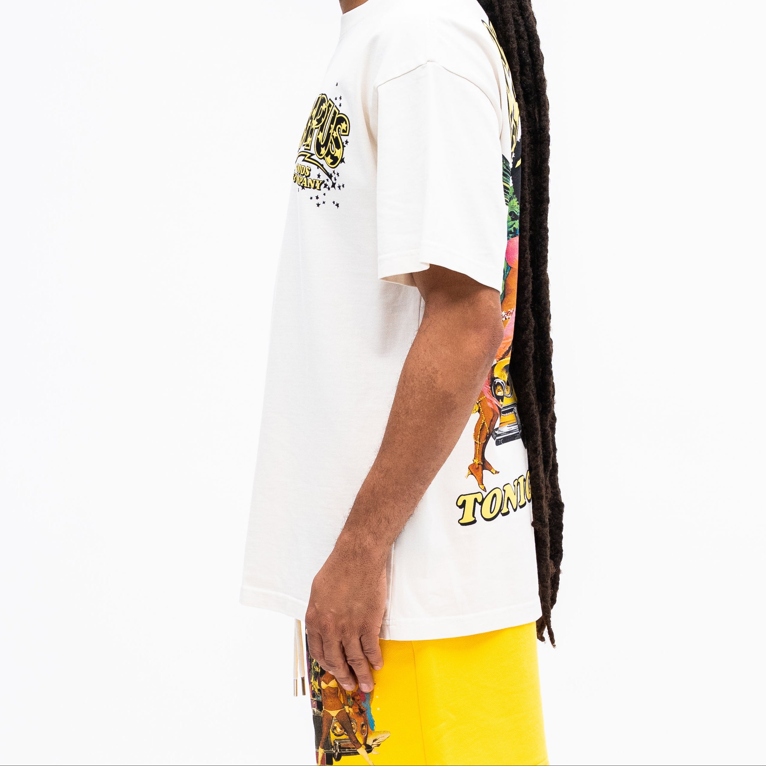 Person wearing a white t-shirt with colorful graphics and yellow shorts on a white background