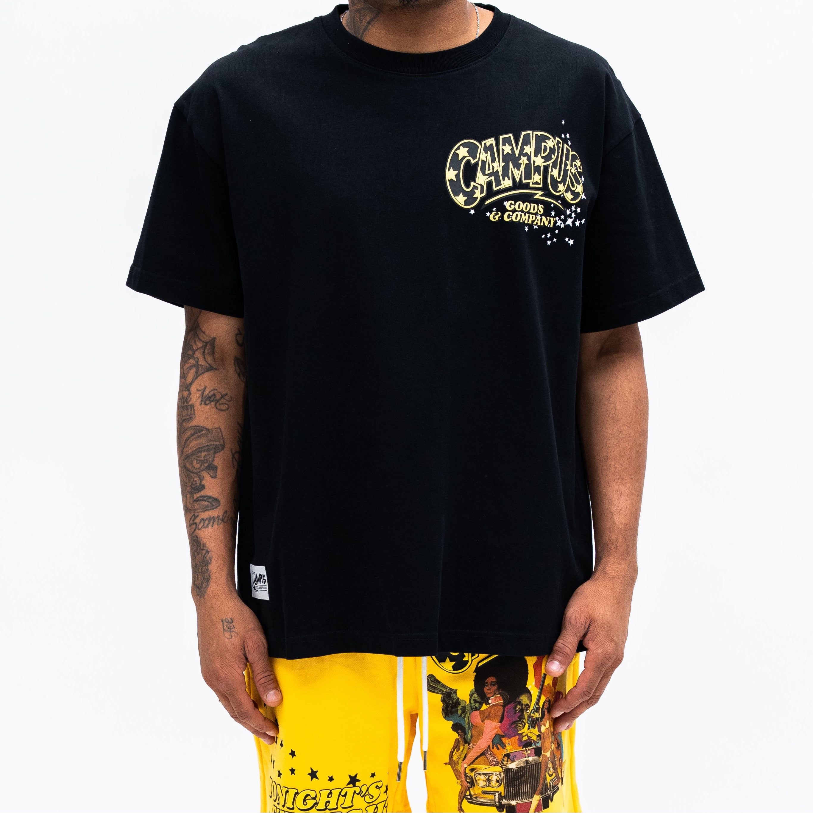 Man wearing a black t-shirt with yellow text and yellow pants on a white background