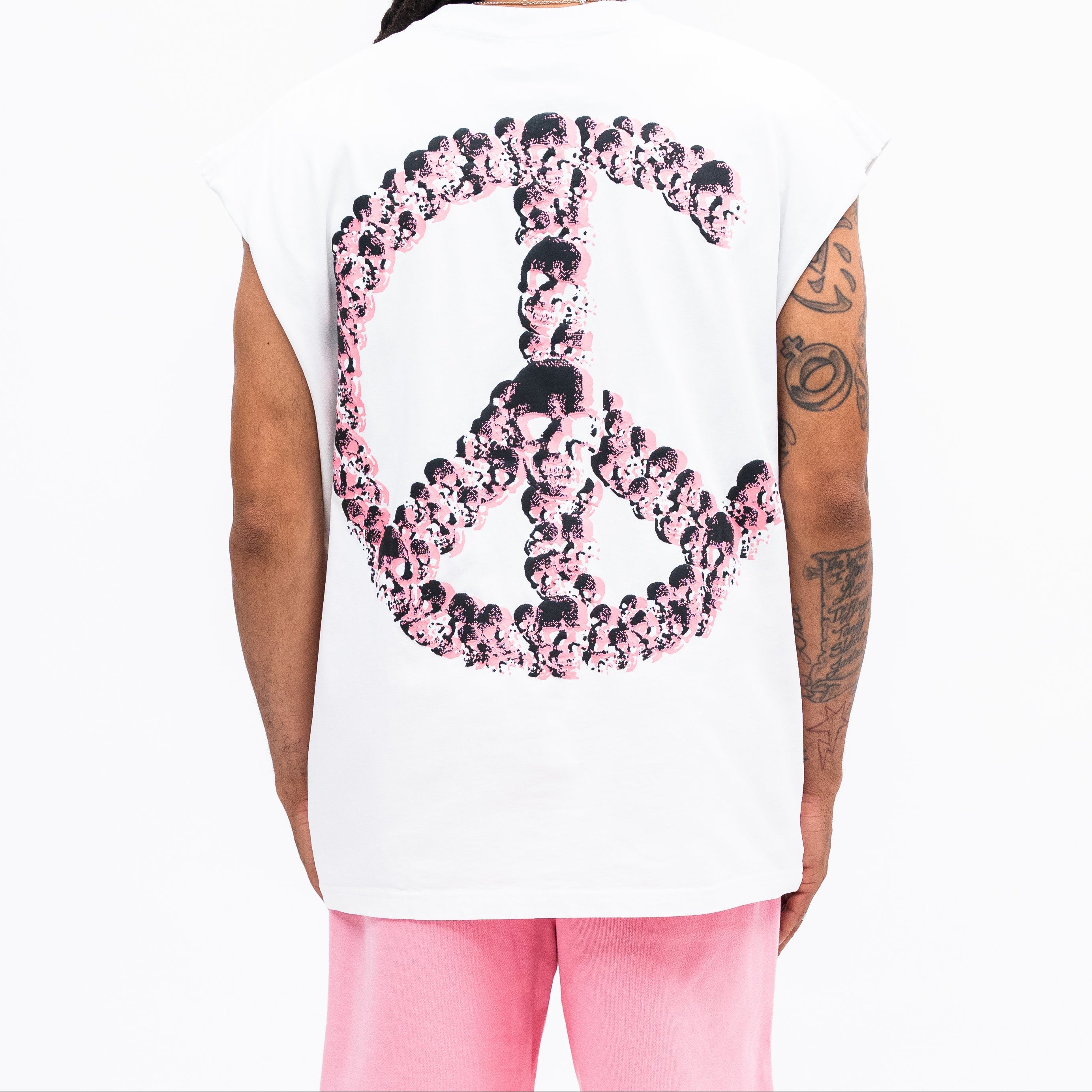 Person wearing a white sleeveless shirt with a pink peace sign design on the back.