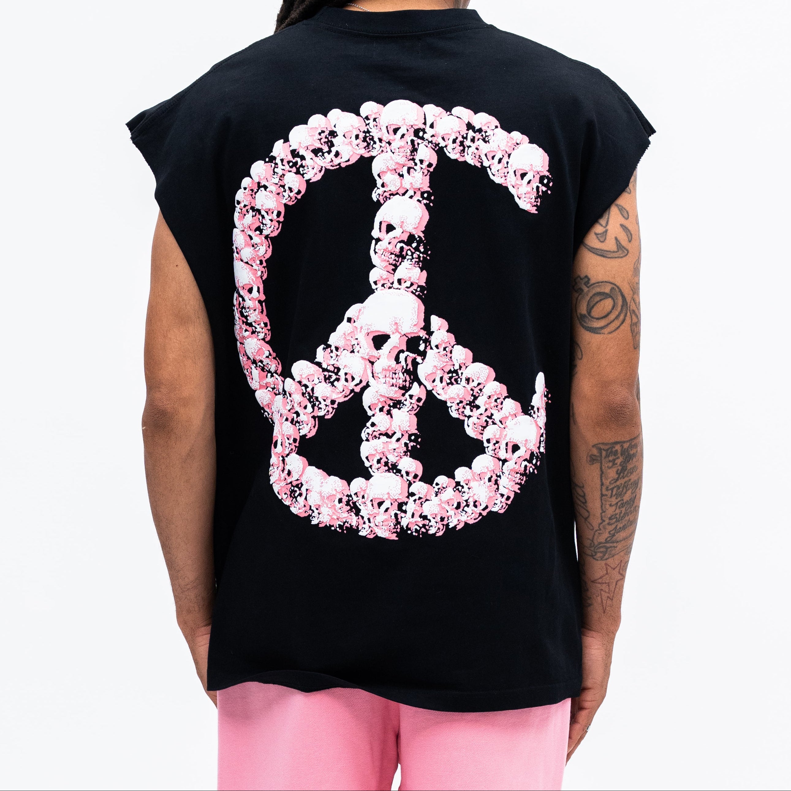 Person wearing a black sleeveless shirt with a pink peace symbol design on the back.
