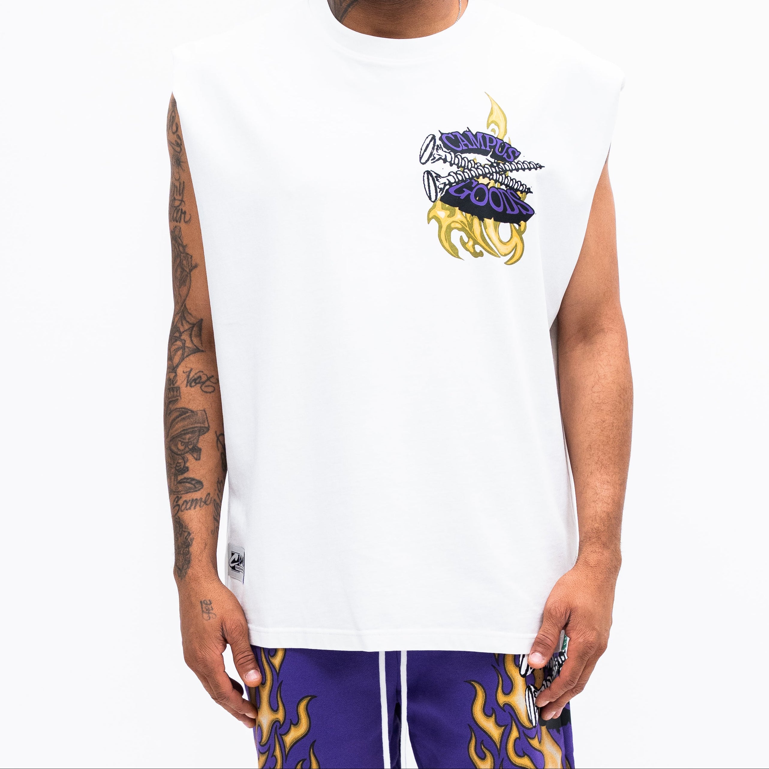 Man wearing a white sleeveless shirt with a logo and purple shorts on a white background