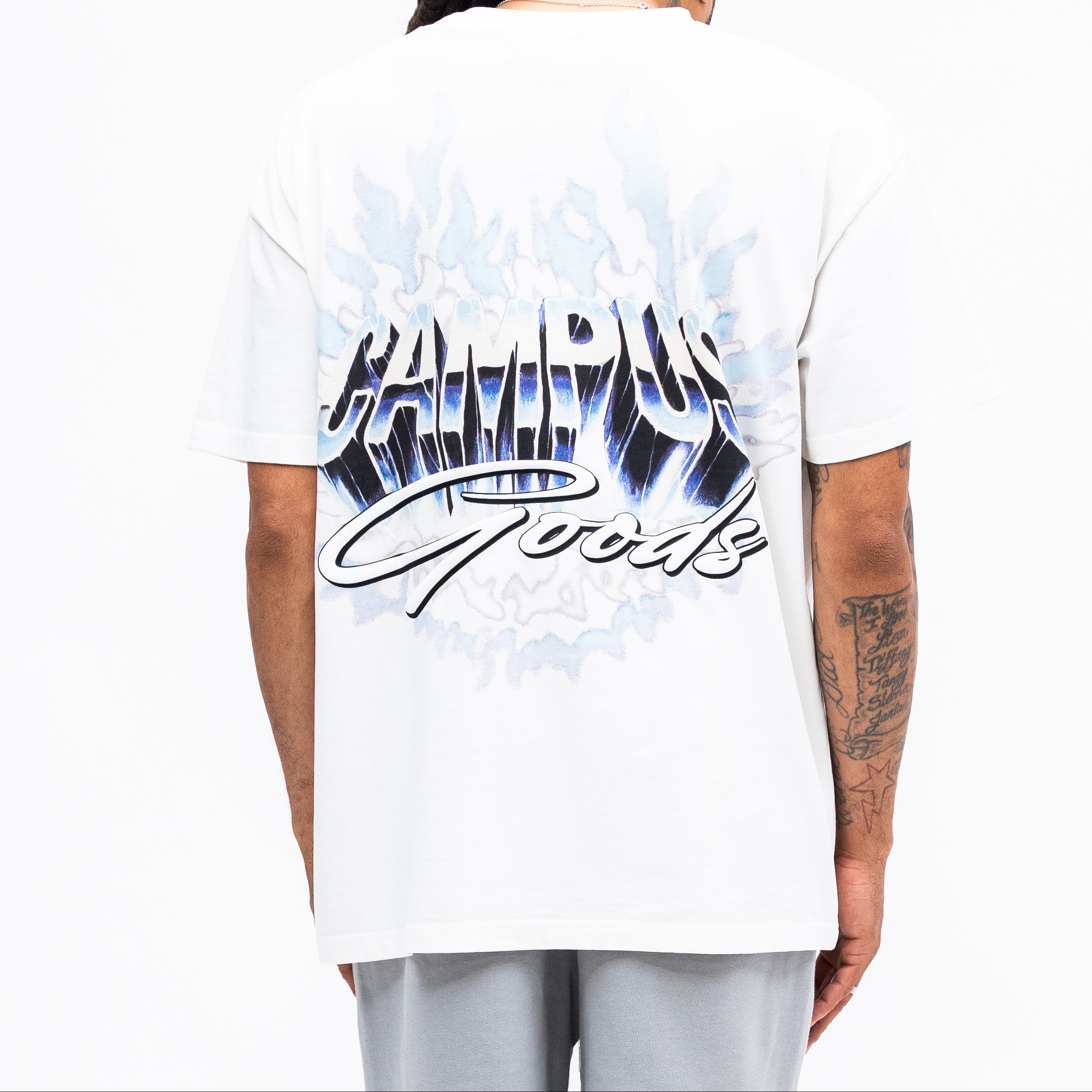 Person wearing a white t-shirt with blue and black graphics on the back