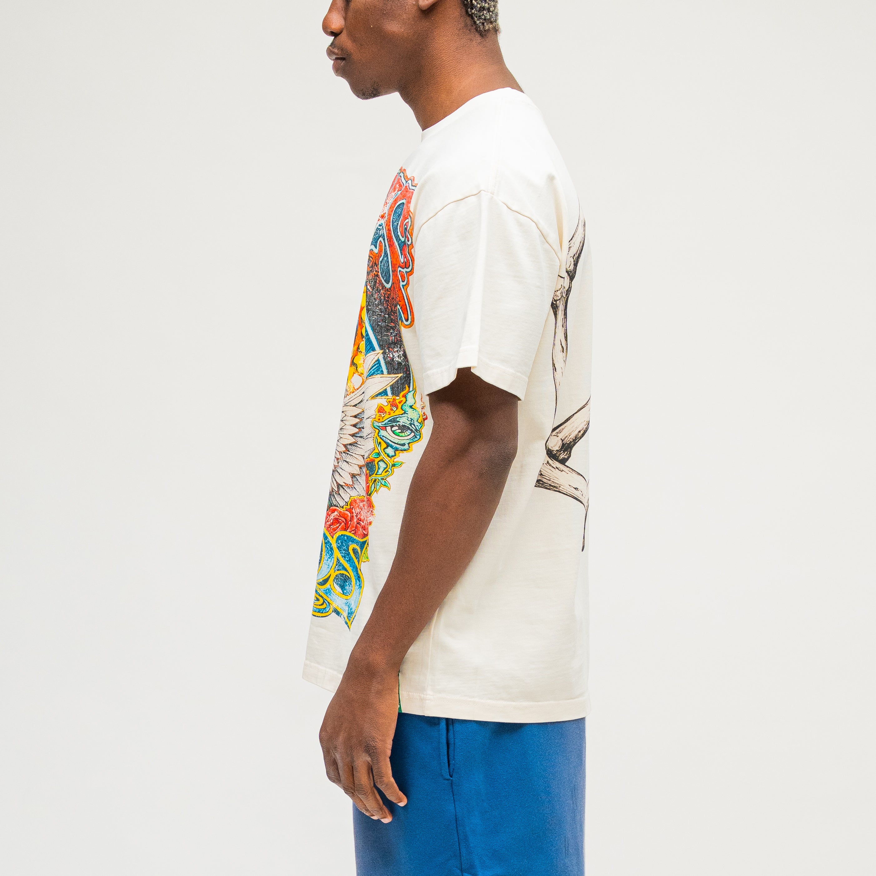 Campus Goods Psychedelic Tee in cream, side view with skull, wings, roses, and all-seeing eye graphic