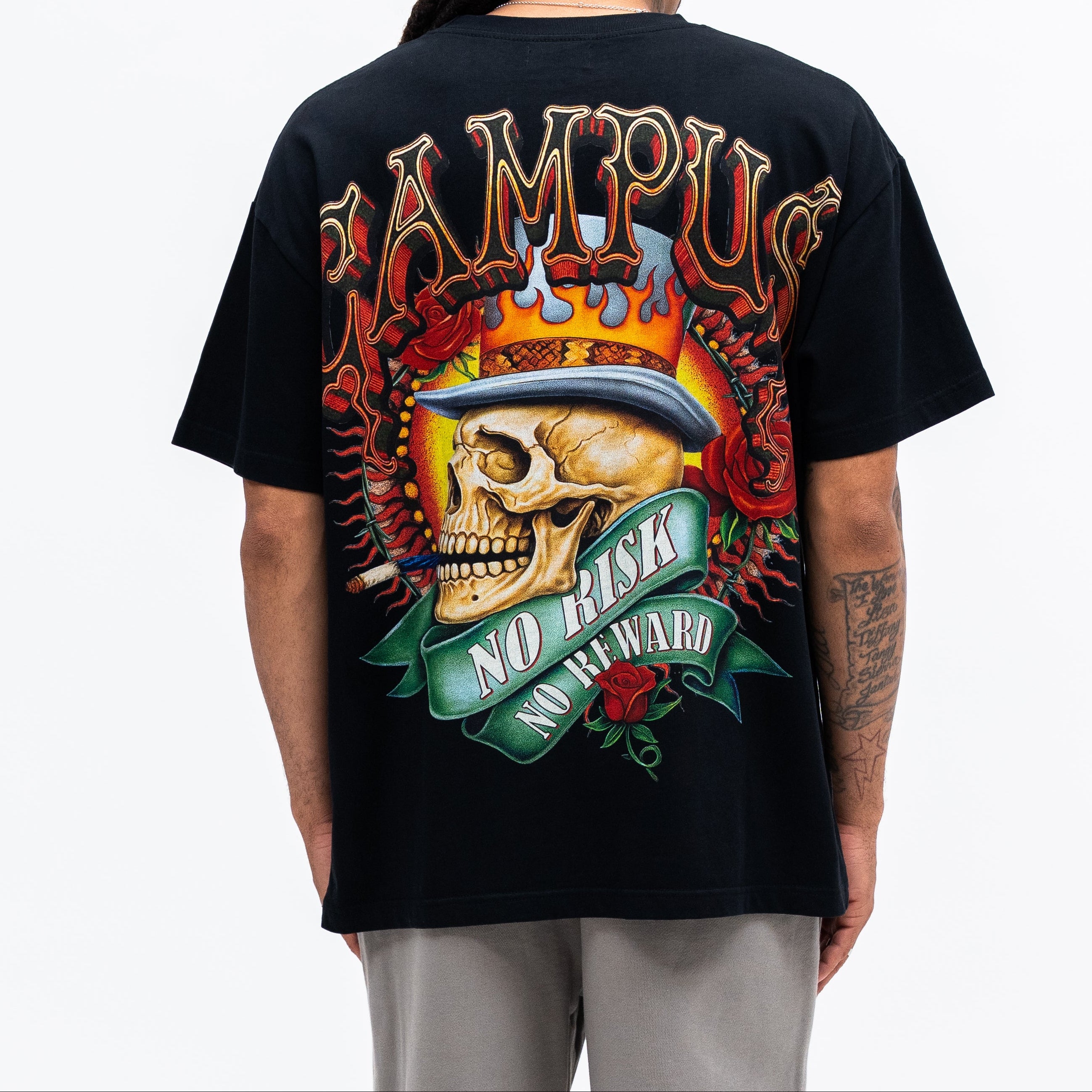 Person wearing a black t-shirt with a colorful graphic design on the back, featuring a skull and text.
