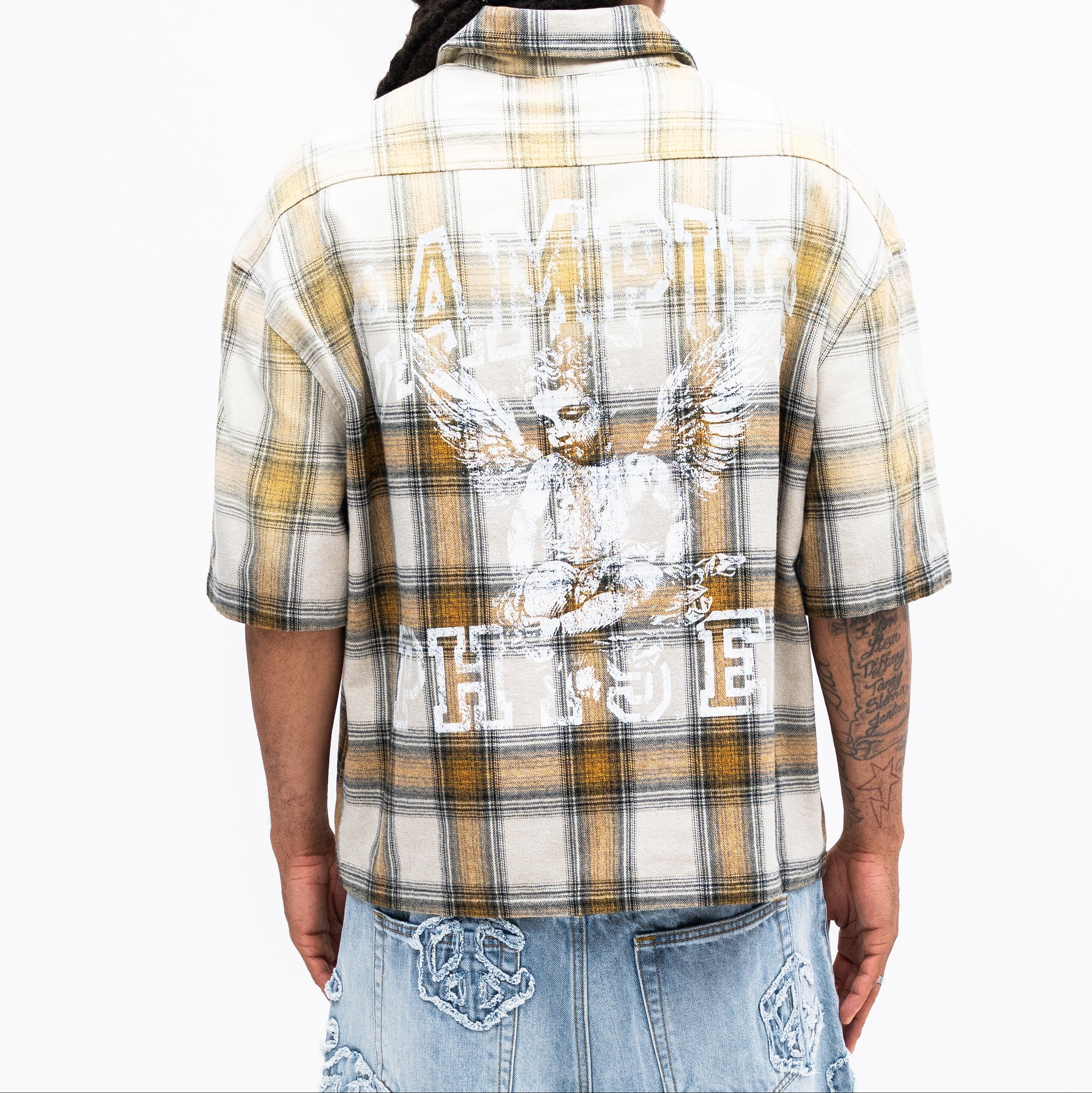 Person wearing a plaid shirt with graphic design and text, standing against a white background